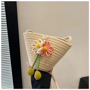 Detail of woven straw bag featuring crochet flowers, green tassels and pearl button closure