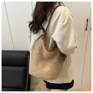 Detail of woven straw tote bag featuring leather handles and fine hollow mesh texture