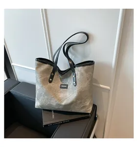 Close-up of vintage grey tote bag with FASHION label on a leather bench setup