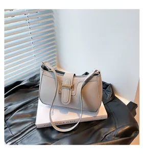 Detailed close-up of a vintage beige leather underarm bag with gold metal buckle closure