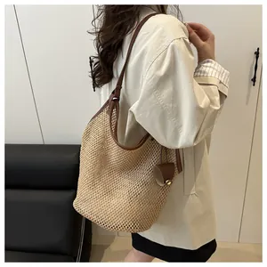 Close-up of lightweight hollow straw mesh tote bag with brown leather shoulder straps