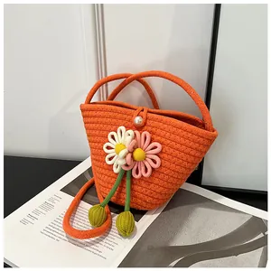 Close-up of orange woven bucket bag with handmade daisy flowers and pearl closure detail