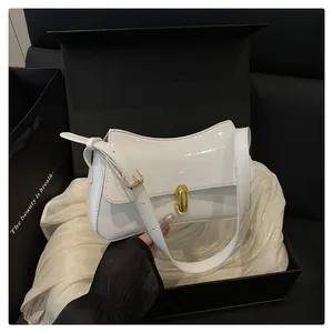 Close-up of white patent leather shoulder bag with gold clasp in premium gift box