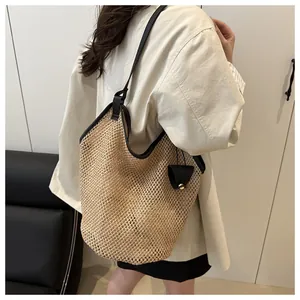 Detail of hollow woven straw beach tote bag with black faux leather strap and pouch