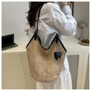 Detail view of large straw woven tote bag with black leather straps and mesh texture
