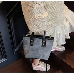 Detail of grey leather bucket bag with gold rivets and handle shown on stairs