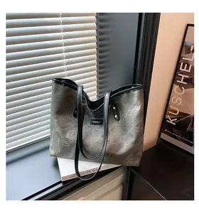 Detail of grey-green canvas tote bag with black leather handles and Fashion tag