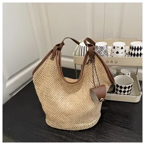 Detail of hollow woven beach tote bag with brown leather handles and side charm