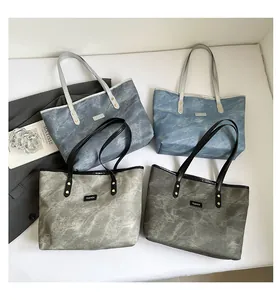Vista piatta di quattro grandi borse tote in texture marmo grigio e blu con cinturini