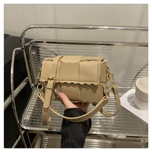 Detail of woven beige leather crossbody bag with golden chain and wave edge cut
