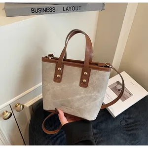 Detail of canvas and brown leather stitching on a bucket bag with gold rivets