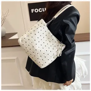 Close-up of white quilted tote bag with rabbit patterns and a pearl bow charm detail