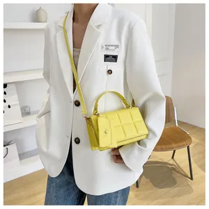 Detail of yellow quilted crossbody bag with matching pouch on model in white blazer