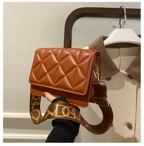 Close-up of brown quilted leather crossbody bag with jacquard wide strap and gold hardware