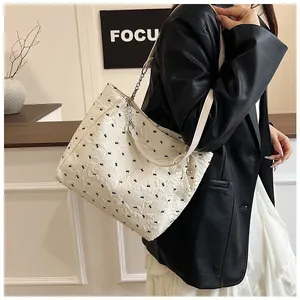 Close-up of white embossed tote bag with black bows and pearl tassel accessory