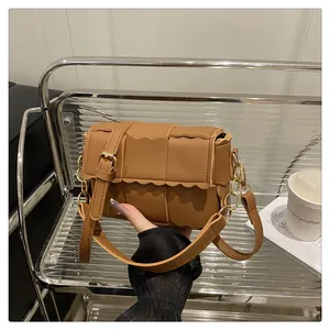 Close-up of brown woven shoulder bag with scalloped edges and gold metal hardware