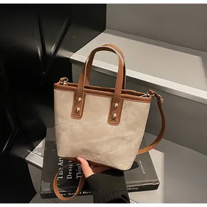 Detail of vintage canvas bucket bag with brown leather trim and metallic rivets