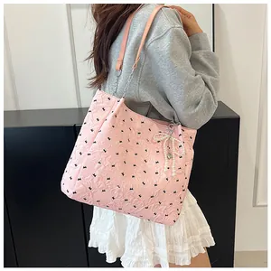 Detail of pink bow tote bag with textured fabric, metal chain strap and pearl charm