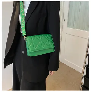 Detail of green crossbody bag featuring triangle quilting and wide patterned strap