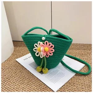 Close-up of green woven bucket bag with 3D floral details and a pearl button closure