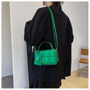 Detail of green quilted crossbody bag featuring a matching mini zip pouch and gold hardware