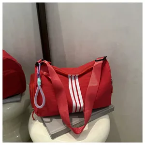 Detail of red travel bag featuring white triple stripes and purple braided keychain