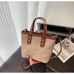 Detail of beige canvas and brown leather bucket bag with elegant gold rivet accents