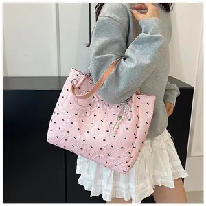 Detail of pink quilted tote bag with black bunny prints and a pearl bow charm