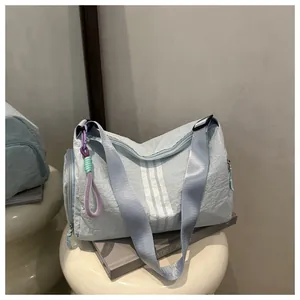 Detail of light blue gym bag with white stripes, adjustable strap, and woven tassel detail