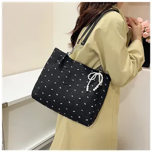 Detail of black tote bag with white rabbit prints and decorative pearl bow pendant