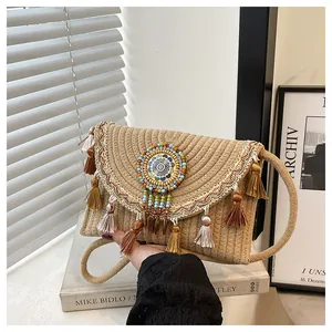 Detailed close-up of bohemian woven straw bag with colorful tassels and beaded mandala