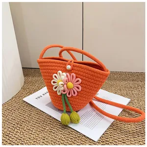 Detail of woven orange flower bag featuring white pearl button and floral knit accents