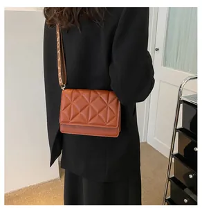 Close-up of brown quilted crossbody bag with stylish wide patterned shoulder strap