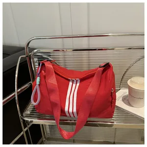 Detail of red nylon sports bag showing white stripes and a colorful woven zipper pull