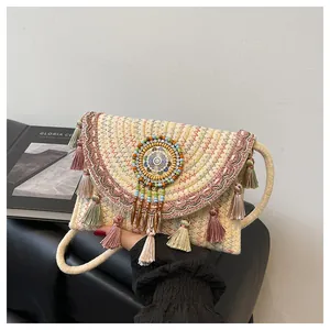 Detailed straw envelope bag with ethnic embroidery, colorful tassels, and rope strap