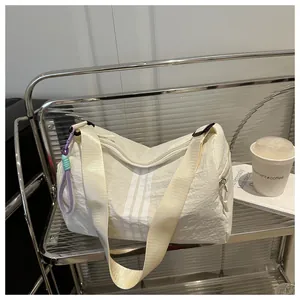 Detail of off-white nylon gym bag with vertical stripes and woven zipper pull charms