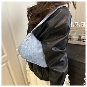 Close-up of light blue denim baguette bag featuring colorful embroidered bow patterns