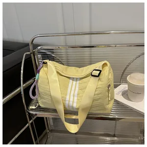 Macro detail of lightweight yellow nylon fitness bag with white stripes and purple charm