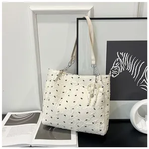 Detail of off-white tote bag featuring jacquard bow patterns and pearl charm accessory