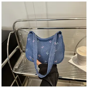 Detail of denim handbag with pink bow patterns and reinforced handles in a casual setting