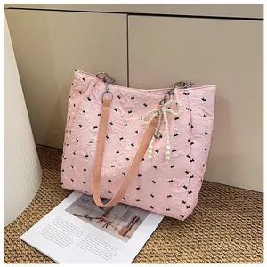 Detail of pink quilted tote bag with black bow embroidery and pearl charm pendant