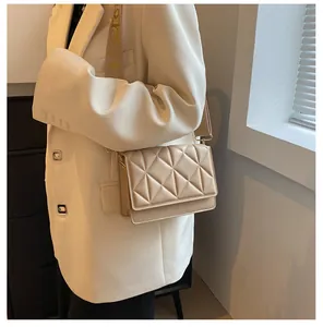 Detail of beige quilted crossbody bag with wide shoulder strap worn by a model