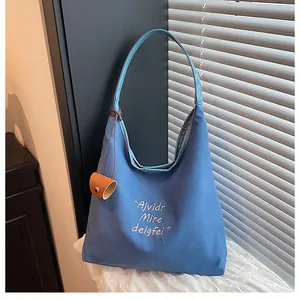 Close-up of sky blue canvas tote bag with white artistic lettering and leather pendant