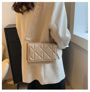 Close-up of beige quilted crossbody bag with stylish jacquard woven wide strap