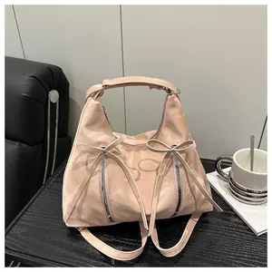 Detail der rosa Schultertasche mit Schleifen und Silberreißverschlüssen auf Holztisch