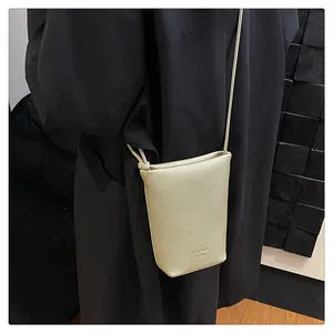 Detail showing champagne gold crossbody phone bag with lychee grain leather texture