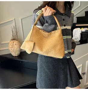 Detail of light brown leather woven hobo bag with knotted strap and mini bag charm