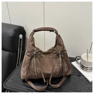 Detail der braunen Handtasche mit zwei vertikalen Reißverschlüssen und Schleifen