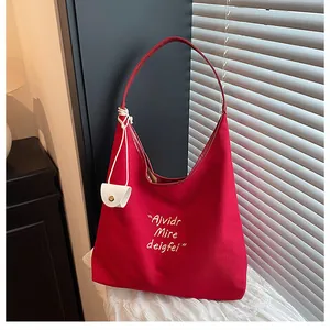 Detail of red canvas tote bag with embroidery and small white hanging pouch accessory