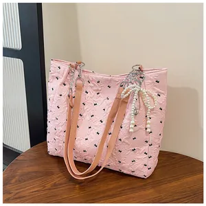 Detail of pink quilted tote bag with black bow patterns and elegant pearl charm